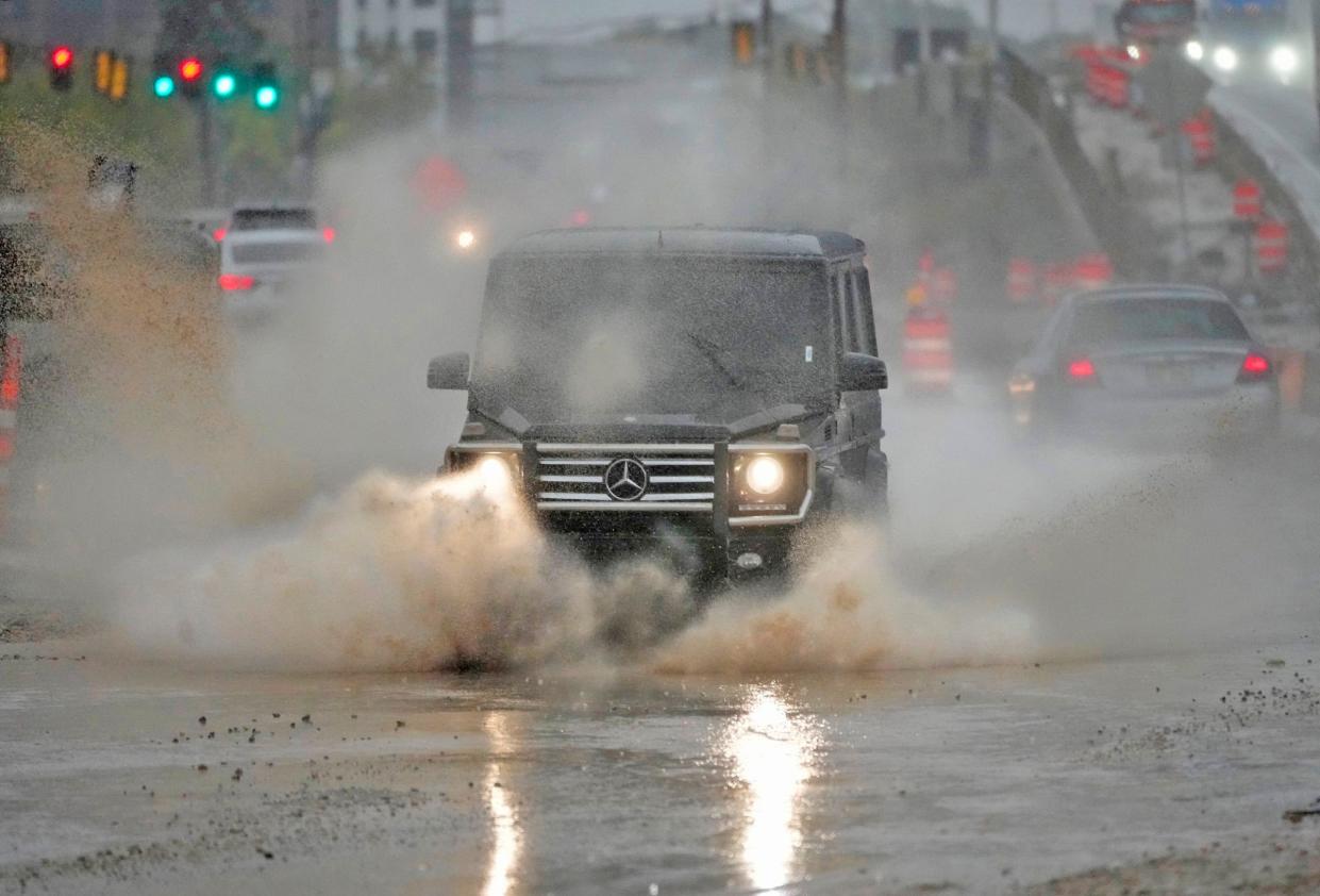 A motorist drives through a puddle of water along the construction on North Port Washington Road north of West Center Road in Glendale on Friday, Oct. 13, 2023. Rain fell throughout the morning and was expected to continue through the day into Saturday.