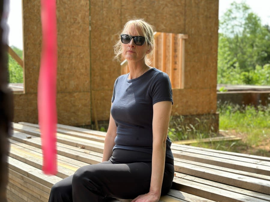 Lisa Labelle sits on a stack of lumber left at her unfinished Furnace Road Extension home. The wood was delivered for two days of framing in November 2023. Distinctive Homes and Development was supposed to finish her home on April 1, 2024. Labelle said she paid Mario and Joy Cotto $320,000 for the land and home build and has nothing to show for it today. (WJZY Photo/Jody Barr)