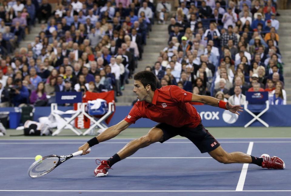 Novak Djokovic of Serbia reaches down to hit a return to Rafael Nadal of Spain during their men's final match at the U.S. Open tennis championships in New York, September 9, 2013. REUTERS/Mike Segar (UNITED STATES - Tags: SPORT TENNIS)