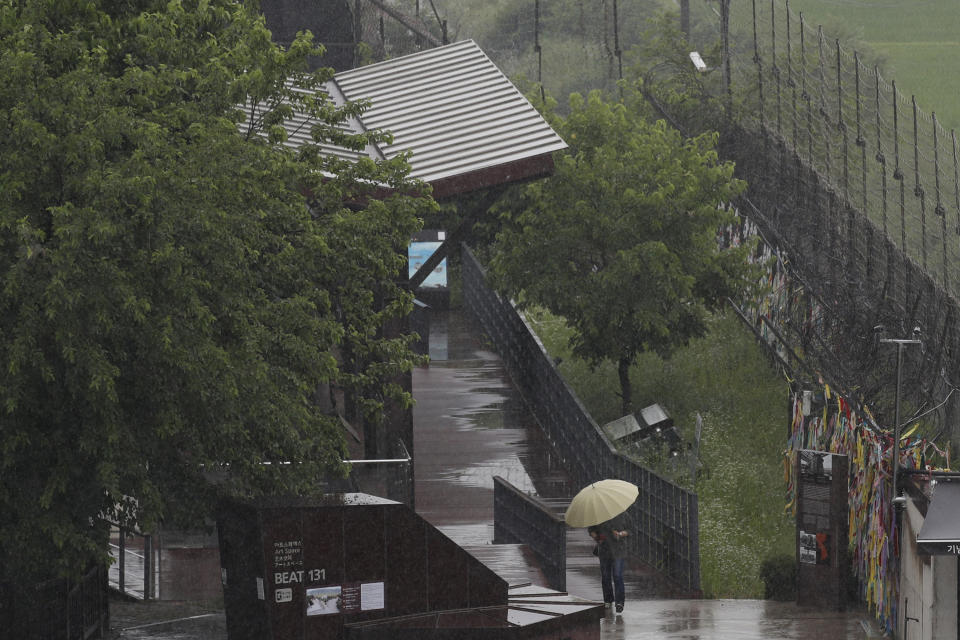 A woman holding an umbrella in rain, walks near the wire fences decorated with ribbons written with messages wishing for the reunification of the two Koreas at the Imjingak Pavilion in Paju, South Korea, Wednesday, June 24, 2020. North Korea said Wednesday leader Kim Jong Un suspended a planned military retaliation against South Korea, possibly slowing the pressure campaign it has waged against its rival amid stalled nuclear negotiations with the Trump administration. (AP Photo/Lee Jin-man)