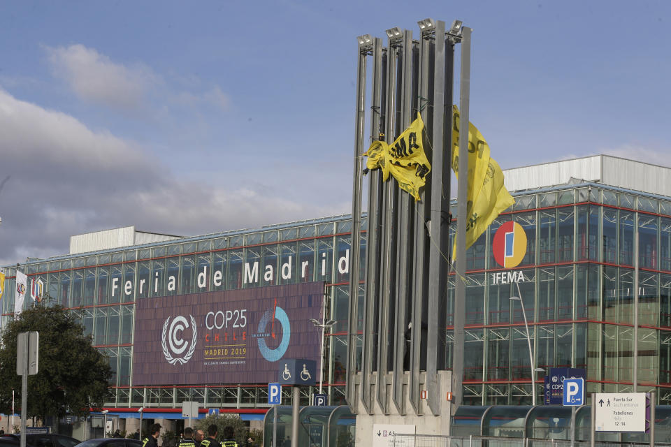 Greenpeace activists try to display banners reading 'The climate is not a business' outside the COP25 climate talks congress in Madrid, Spain, Friday, Dec. 13, 2019. The United Nations Secretary-General has warned that failure to tackle global warming could result in economic disaster. (AP Photo/Paul White)