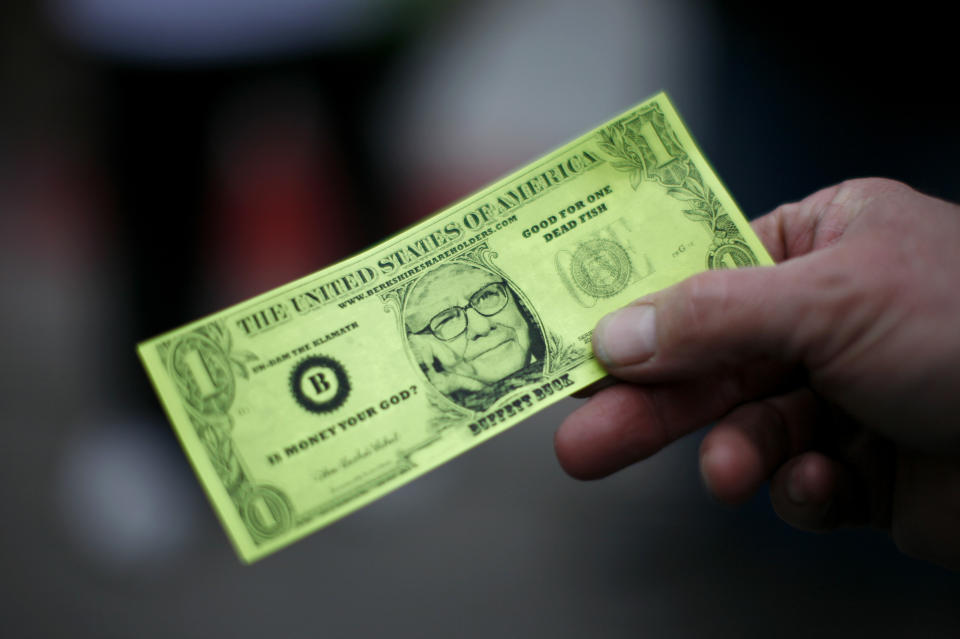 A Berkshire Hathaway shareholder hold a fake dollar bill with the face of billionaire financier and Berkshire Hathaway CEO Warren Buffett during the kick-off celebration at the annual Berkshire Hathaway shareholders meeting in Omaha, Nebraska May 2, 2008. REUTERS/Carlos Barria  (UNITED STATES)