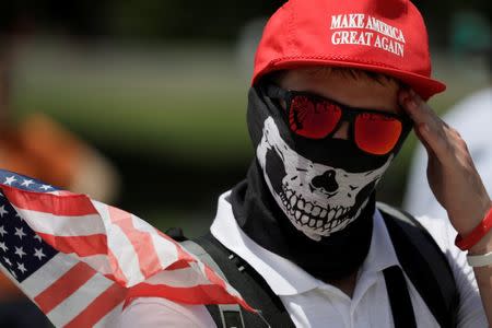 A masked demonstrator in a Donald Trump "Make America Great Again" hat wipes his brow as self proclaimed "White Nationalists", white supremacists and members of the "Alt-Right" gather for what they called a "Freedom of Speech" rally at the Lincoln Memorial in Washington, U.S. June 25, 2017. REUTERS/Jim Bourg