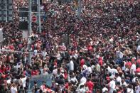 Toronto fans watch a man climb down a poll as they fill the streets in front of the city hall, during the Toronto Raptors NBA Championship celebration parade at Nathan Phillips Square in Toronto