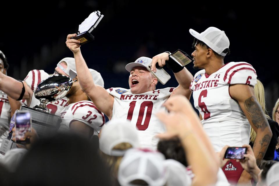 Dec 26, 2022; Detroit, Michigan, USA; New Mexico State University quarterback Diego Pavia (10) shows off his game MVP trophy as he and his teammates celebrate their win over Bowling Green State University in the 2022 Quick Lane Bowl at Ford Field.