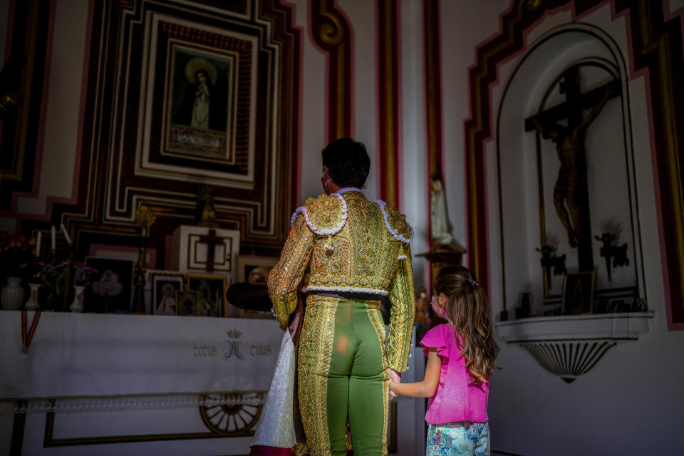 A bullfighter prays with a girl inside of a chapel before the start of a bullfight amid the coronavirus pandemic at Las Ventas bullring in Madrid, Spain, Sunday, July 4, 2021. (AP Photo/Manu Fernandez)