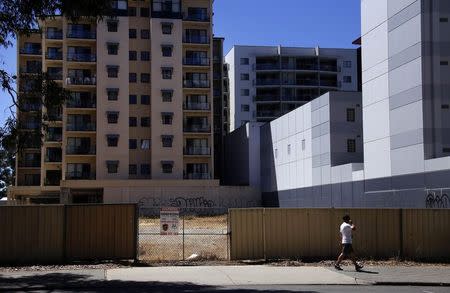 A man walks past a vacant block next to apartment buildings in the Western Australian capital city of Perth March 5, 2015. REUTERS/David Gray