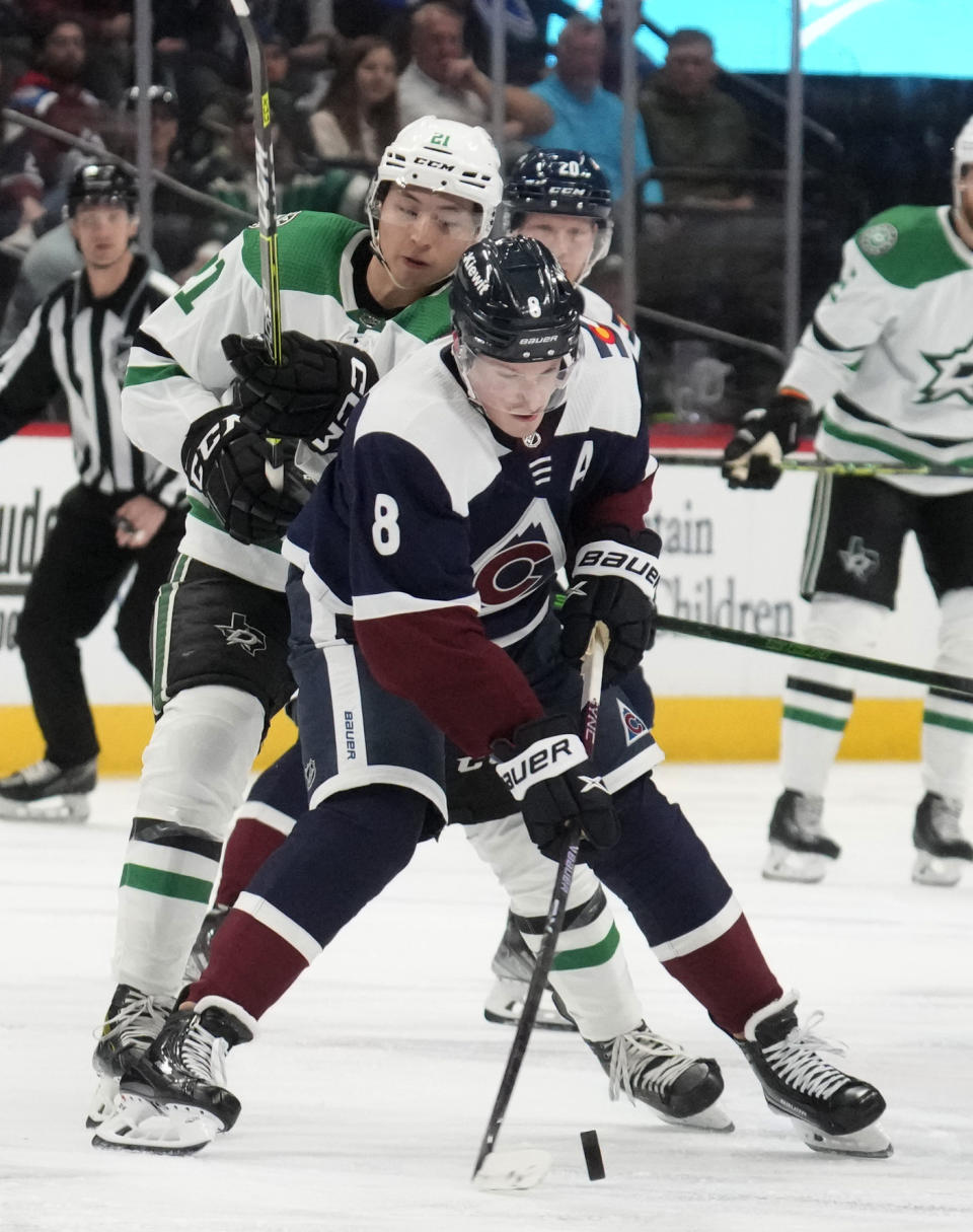Colorado Avalanche defenseman Cale Makar, front, struggles to collect the puck as Dallas Stars left wing Jason Robertson defends in the second period of an NHL hockey game Saturday, April 1, 2023, in Denver. (AP Photo/David Zalubowski)