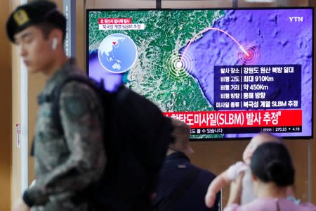 A South Korean soldier walks past a TV broadcasting a news report on North Korea firing a missile that is believed to be launched from a submarine, in Seoul