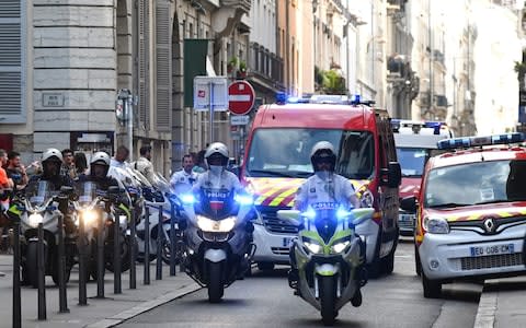 French police escort the emergency services following a suspected package bomb blast along a pedestrian street in the heart of Lyon, southeast France - Credit: PHILIPPE DESMAZES/AFP