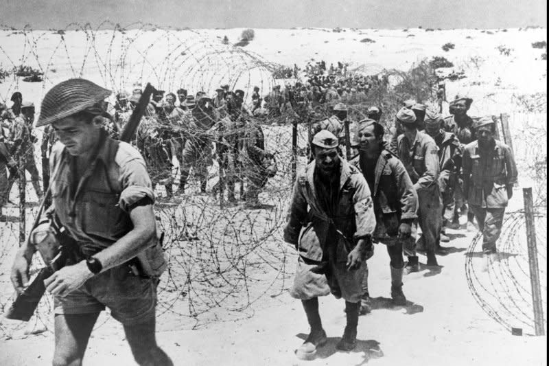 Italian prisoners of war captured in the El Alamein area entering the "cage" preceeded by their guard. Picture taken ca. Nov. 1942. File Photo by OWI/UPI