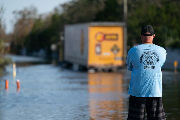 An Okeechobee County sheriff's deputy watches a tractor-trailer drive down a flooded street to reach a community cutoff of by floodwaters from the Peace River in the wake of Hurricane Ian on October 4, 2022, in Arcadia, Florida. Fifty miles inland, and nearly a week after Hurricane Ian made landfall on the Gulf Coast of Florida, the record-breaking floodwaters in the area are receding to reveal the full effects of the storm.