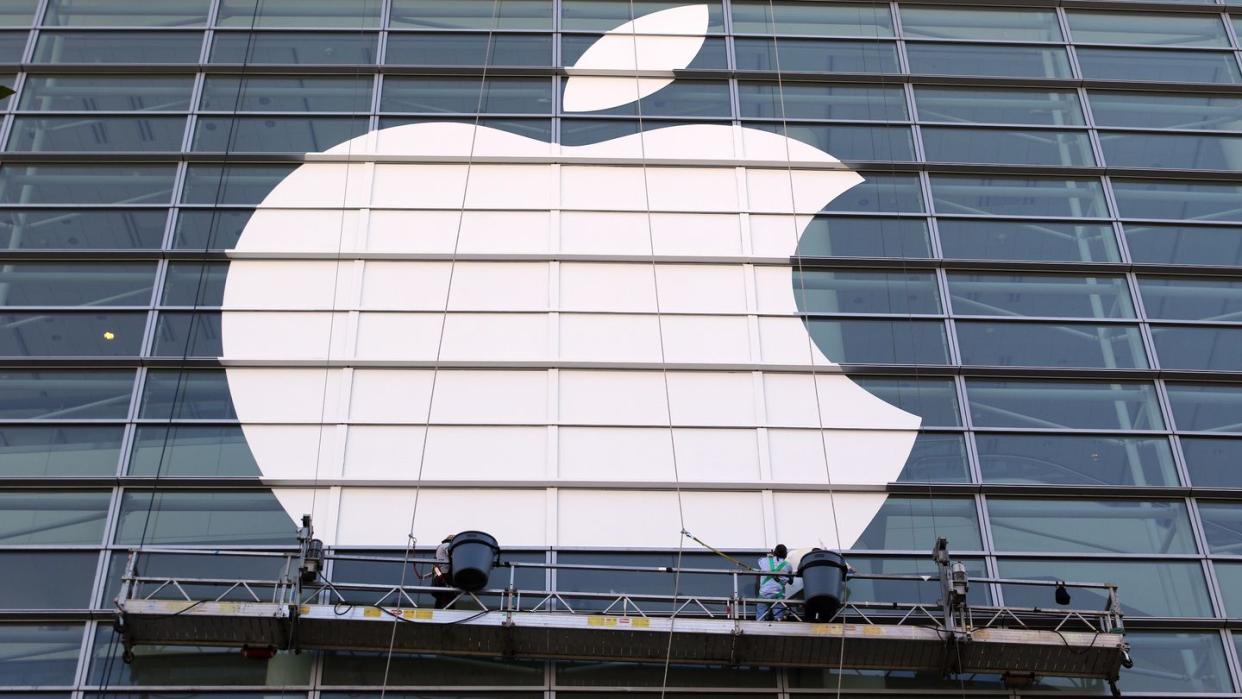 Arbeiter bringen ein übergroßes Apple-Logo an einer Glasfassade in San Francisco an.