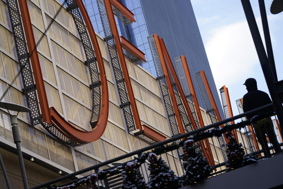 A shopper pauses to look at a sign spelling out the word "Denver" while in search of after-Christmas bargains in shops in the Denver Pavilions Tuesday, Dec. 29, 2020, in downtown Denver. (AP Photo/David Zalubowski)