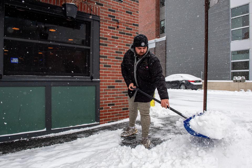 A person clears snow in front of a business in Manchester, New Hampshire (AFP via Getty Images)