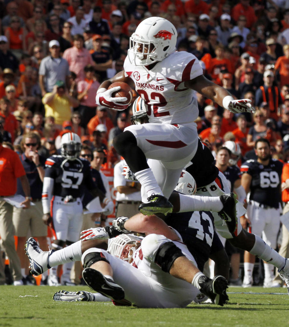 Arkansas running back Jonathan Williams (32) hurdles a pile of players as he carries the ball for a first down against Auburn during the first half of an NCAA college football game on Saturday, Aug. 30, 2014, in Auburn, Ala. (AP Photo/Butch Dill)