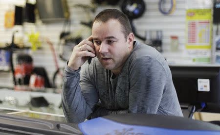 Fabian Zakharov speaks with a client from Cuba using his cellphone in his Zakharov Auto Parts shop in Hialeah, Florida, February 4, 2015. REUTERS/Javier Galeano