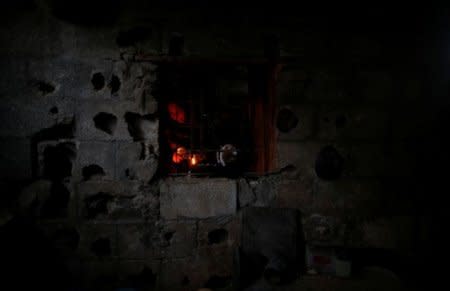 FILE PHOTO: A Palestinian woman is seen from the window of her kitchen as she uses a candle light to prepare food during a power cut in Beit Lahiya town, in the northern Gaza Strip, July 13, 2017. REUTERS/Mohammed Salem