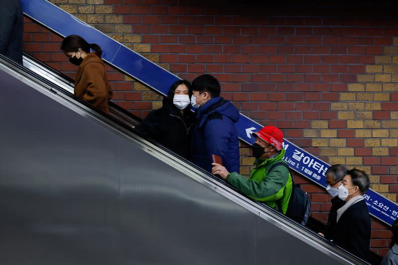 A couple wearing mask rides on an escalator at a subway station amid the coronavirus disease (COVID-19) pandemic in Seoul