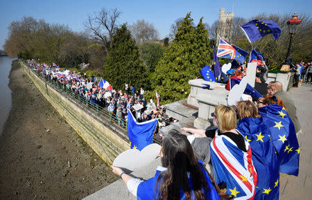An EU flag is waved by an anti-Brexit protester looking over a pro-Brexit March to Leave demonstration as it walks along the River Thames, in London, Britain March 29, 2019. REUTERS/Toby Melville