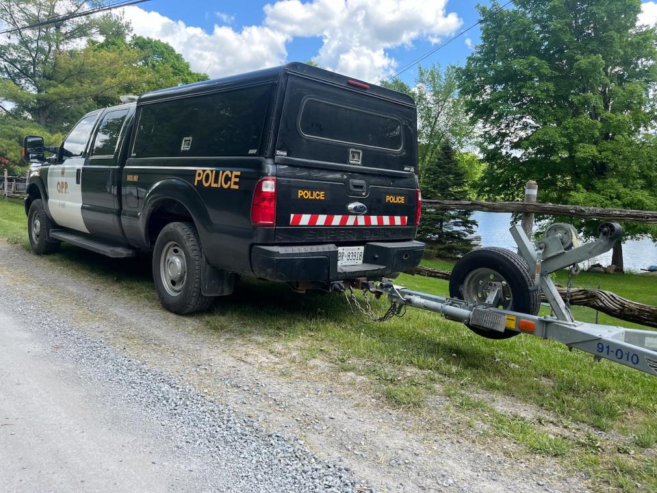 An Ontario Provincial Police vehicle is parked near the shore of Bobs Lake on May 19, 2024. Three people were killed and five more injured after two boats collided on the lake north of Kingston, Ont., the night before.