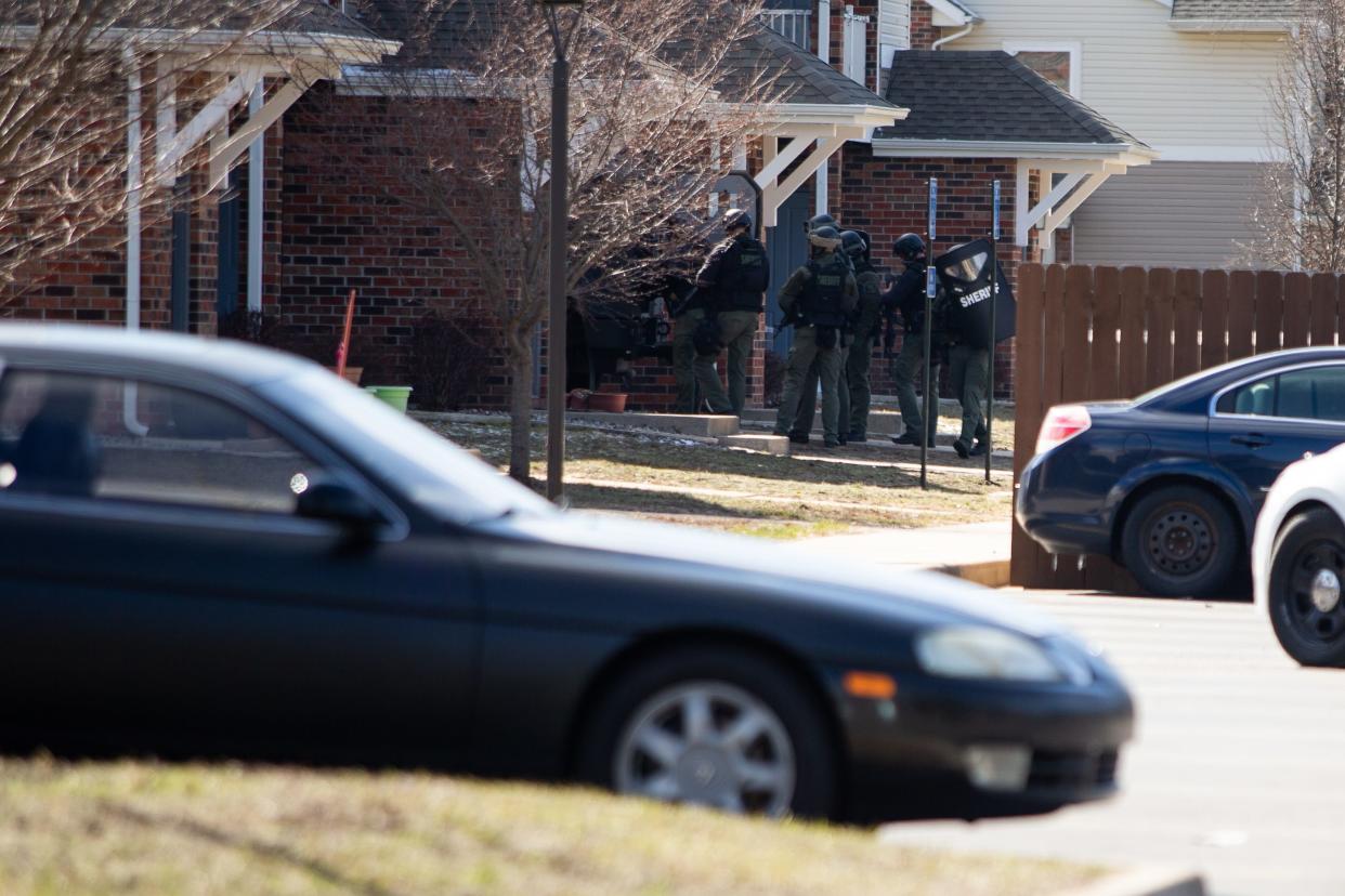 Members of the Ottawa County Sheriff's office stand outside an apartment where a suspect from Monday morning's shooting at Adient Manufacturing is believed to be inside Monday, March 28, 2022. The shooting left one woman with minor injuries to her hand.