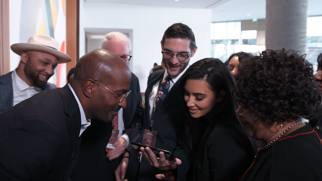 Van Jones, Kim Kardashian, Alice Johnson, Louis L. Reed and Alex Guditch of #cut50 huddle over a cell phone to watch President Trump deliver a speech on the First Step Act in a scene from THE FIRST STEP.