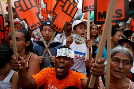 FILE PHOTO: A supporter of Venezuelan presidential candidate Henri Falcon, with a fake hundred dollar bill on his forehead, shouts slogans during a campaign rally in Caracas, Venezuela May 14, 2018. REUTERS/Carlos Garcia Rawlins/File Photo