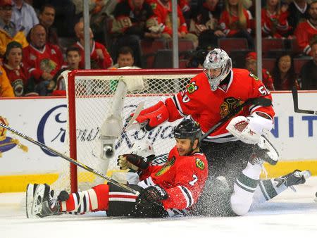 May 11, 2014; Chicago, IL, USA; Minnesota Wild center Cody McCormick (8) slides into the net between Chicago Blackhawks defenseman Brent Seabrook (7) and goalie Corey Crawford (50) during the third period of game five of the second round of the 2014 Stanley Cup Playoffs at the United Center. Chicago won 2-1. Mandatory Credit: Dennis Wierzbicki-USA TODAY Sports