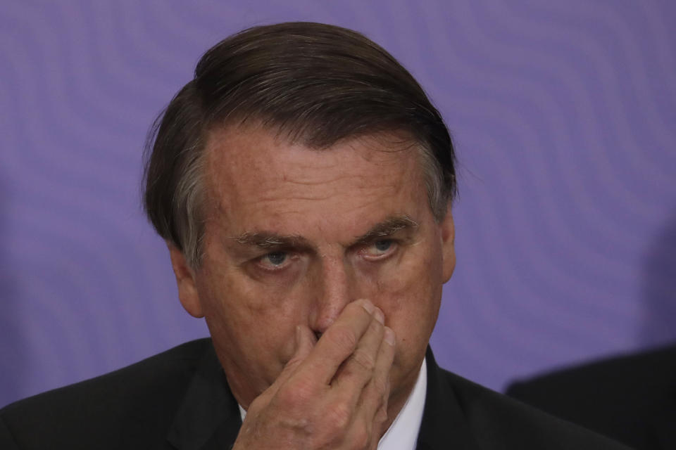 Brazilan President Jair Bolsonaro touches his nose during a ceremony presenting his nation's National Vaccination Plan Against COVID-19 at Planalto presidential palace in Brasilia, Brazil, Wednesday, Dec. 16, 2020. (AP Photo/Eraldo Peres)