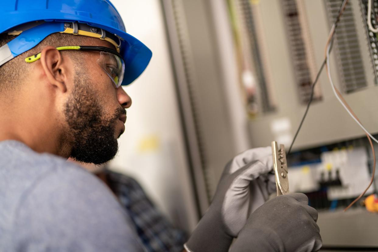 Close up of young electrician cutting wire with cutter.