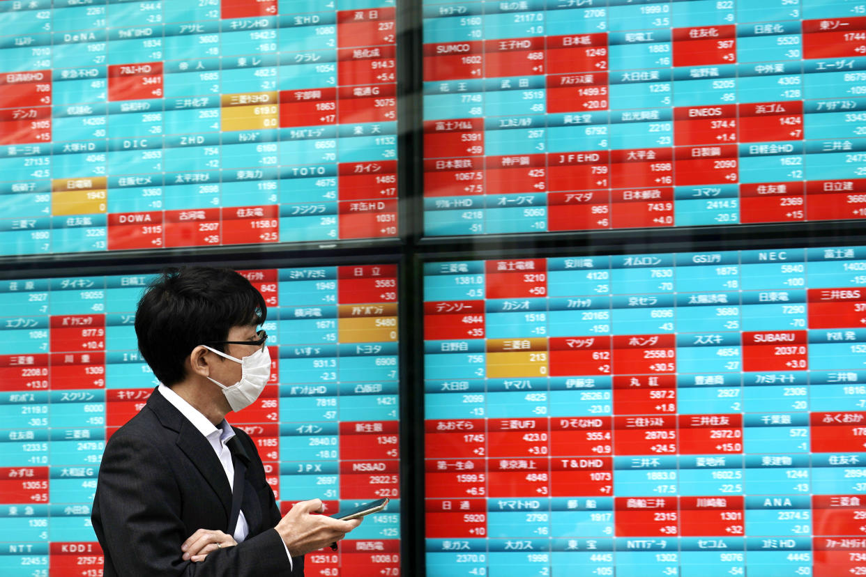 A man looks at an electronic stock board showing Japan's Nikkei 225 index at a securities firm in Tokyo Friday, Oct. 16, 2020. Asian shares were mixed on Friday as investors weighed concerns about the U.S. presidential election and an economic stimulus package, on top of fears of flaring outbreaks of coronavirus. (AP Photo/Eugene Hoshiko)