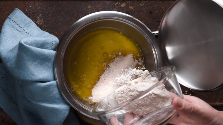 Pouring flour into melted butter in a metal pot