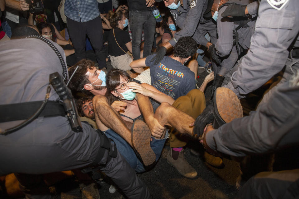 Israeli police officers scuffle with demonstrators during a protest against Israel's Prime Minister Benjamin Netanyahu outside his residence in Jerusalem, early Sunday, July 26, 2020. Protesters demanded that the embattled Israeli leader resign as he faces a trial on corruption charges and grapples with a deepening coronavirus crisis. (AP Photo/Ariel Schalit)