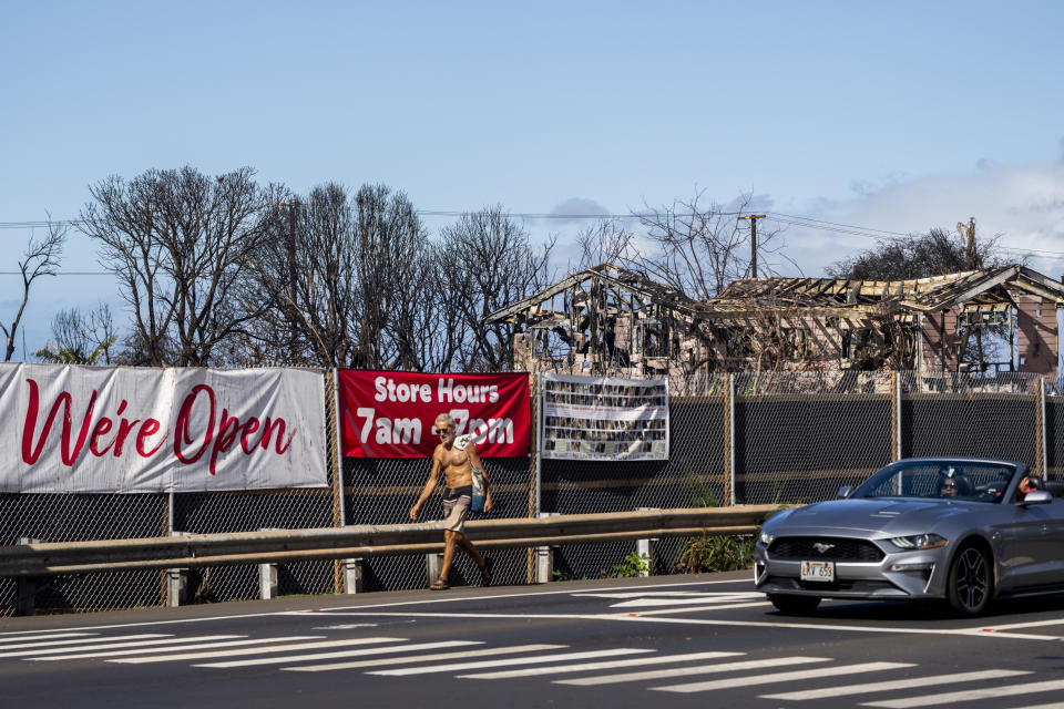 Properties destroyed by wildfire sit behind signs advertising for a nearby Safeway that survived the fire, Wednesday, Dec. 6, 2023, in Lahaina, Hawaii. Cleanup efforts are still underway after the August wildfire that swept through the Lahaina community on Hawaiian island of Maui, the deadliest U.S. wildfire in more than a century. (AP Photo/Lindsey Wasson)