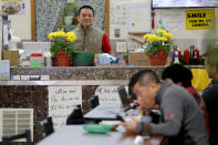 In this Feb. 13, 2020, photo, restaurant owner Phong Nguy watches from his counter as customers eat lunch in the food court at the Mekong Plaza in the Asian district, in Mesa, Ariz. Arizona's freshly crowned Asian District was deep into organizing its night market when news broke that a case of the illness known as COVID-19 was confirmed at nearby Arizona State University. Xenophobic comments on social media and phone calls started almost immediately, according to Arizona Asian Chamber of Commerce CEO Vicente Reid. (AP Photo/Matt York)