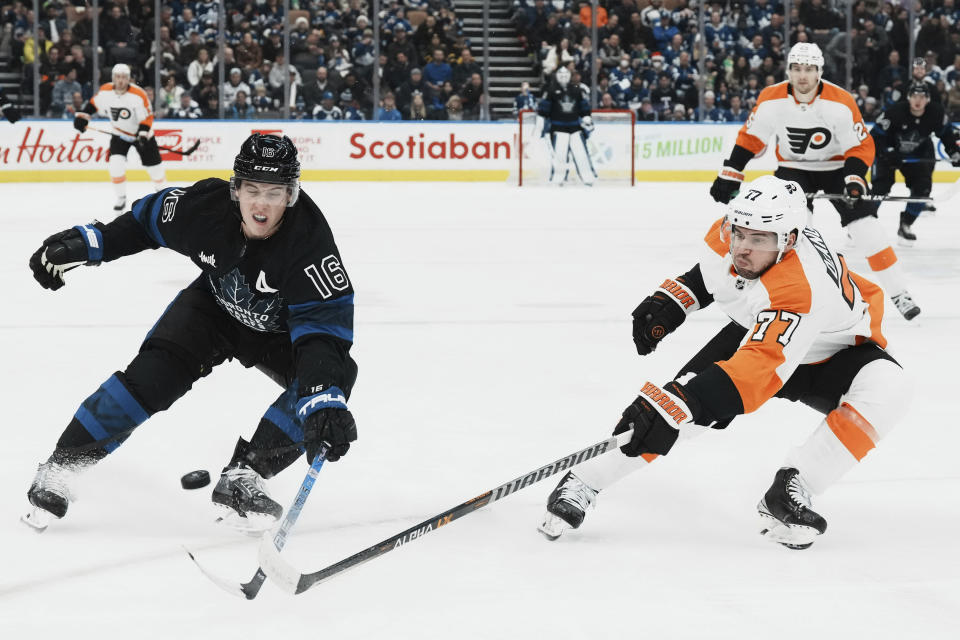 Toronto Maple Leafs right wing Mitchell Marner (16) and Philadelphia Flyers defenseman Tony DeAngelo (77) battle for the puck during the second period of an NHL hockey game, Thursday, Dec. 22, 2022 in Toronto. (Chris Young/The Canadian Press via AP)