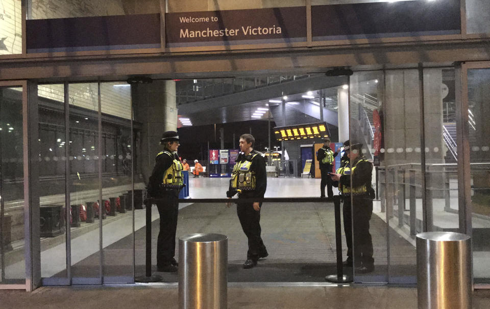 Police at Victoria Station in Manchester, England, late Monday Dec. 31, 2018 after a man had stabbed three people. Two commuters - a man and woman in their 50s - were taken to hospital with knife injuries and a British Transport Police (BTP) officer was stabbed in the shoulder. Police said a man was arrested on suspicion of attempted murder and remains in custody. (Pat Hurst/PA via AP)