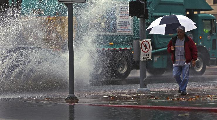 A pedestrian walks under the rain downtown Los Angeles, Friday, Jan. 20, 2017. The second in a trio of storms has arrived in California. Rain, heavy at times, is overspreading the state early Friday and a flash flood warning has been issued for southeastern Sonoma County. Storm warnings are posted up and down the Sierra Nevada and across the mountains of Southern California. (AP Photo/Damian Dovarganes)