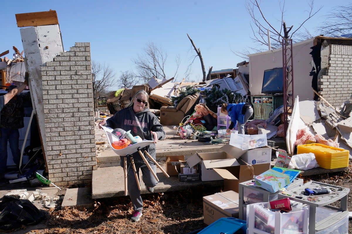 Belinda Penner carries belonging from her cousin’s home in Wayne, Oklahoma, destroyed by a tornado on 13 December 2022 (AP)