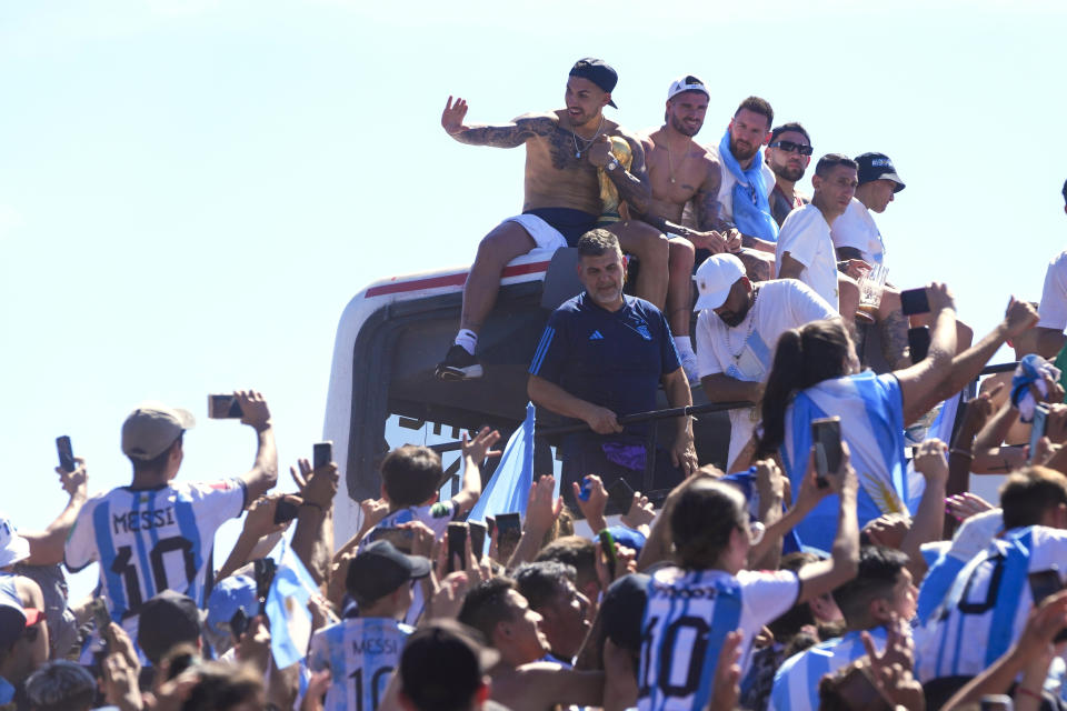 Argentina soccer players, from left, Leandro Paredes, Rodrigo De Paul, Lionel Messi and Nicolas Otamendi sit on the top of a bus during their team's homecoming parade after winning the World Cup tournament in Buenos Aires, Argentina, Tuesday, Dec. 20, 2022. (AP Photo/Natacha Pisarenko)