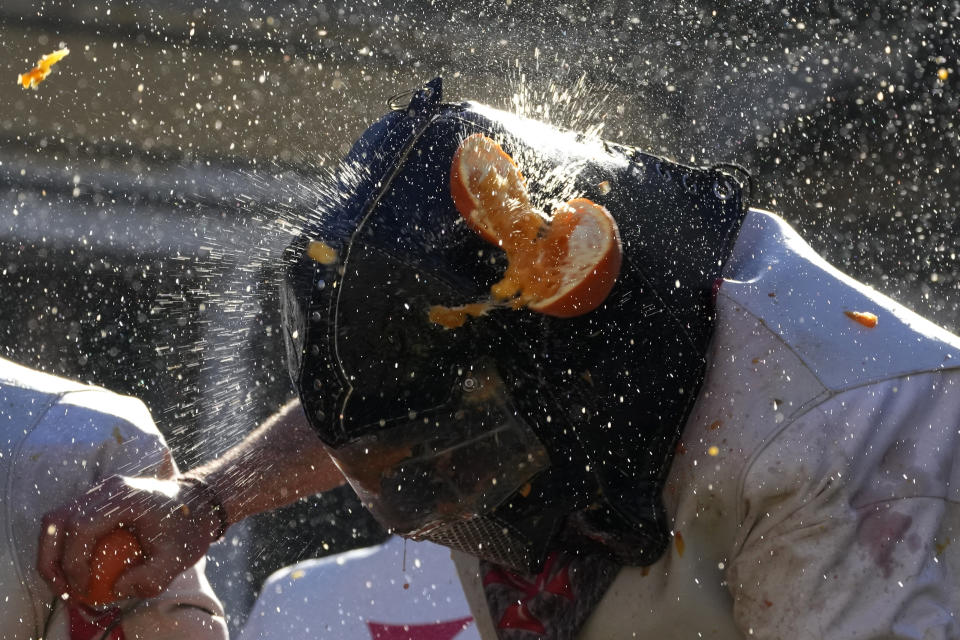 People wearing protection helmets and costumes pelt each other with oranges during the 'Battle of the Oranges" part of Carnival celebrations in the northern Italian Piedmont town of Ivrea, Italy, Tuesday, Feb. 13, 2024. (AP Photo/Antonio Calanni)