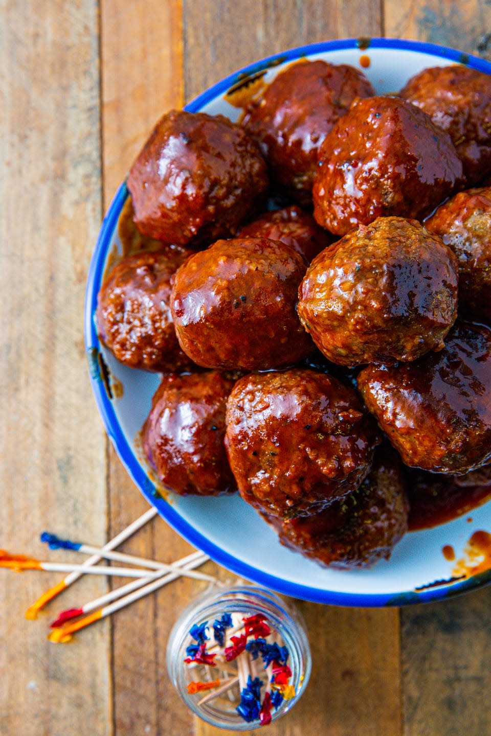 grape jelly meatballs in a blue bowl on a wooden background