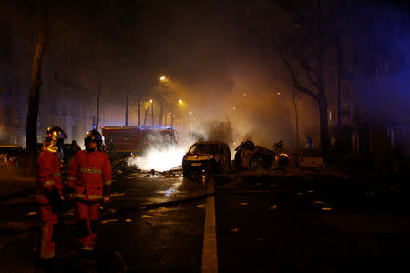 Firemen extinguish burning cars set afire by protesters wearing yellow vests, a symbol of a French drivers' protest against higher diesel fuel taxes, during clashes near the Place de l'Etoile in Paris, France, December 1, 2018. REUTERS/Stephane Mahe