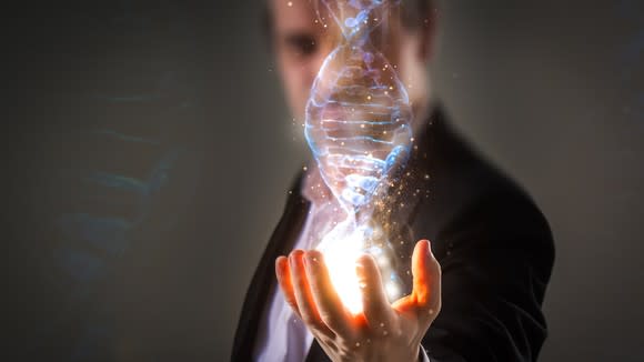 A businessman holds an image of a double helix in the palm of his hand.