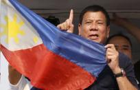 Presidential candidate Rodrigo "Digong" Duterte holds the national flag during election campaigning for May 2016 national elections in Malabon, Metro Manila in the Philippines April 27, 2016. REUTERS/Erik De Castro