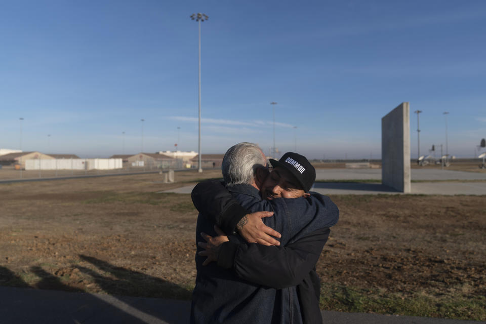 Rapper Bobby Gonzalez, right, a former prisoner at Valley State Prison, hugs resident Jesus Cecena, 61, in the prison yard in Chowchilla, Calif., Friday, Nov. 4, 2022. Gonzalez was released on parole from the prison in September of 2019, after serving 16 years of a 25-year sentence as a juvenile offender. He left a mark at the prison and on the California Department of Corrections and Rehabilitation, emerging as an established artist by the name of "Bobby Gonz." (AP Photo/Jae C. Hong)