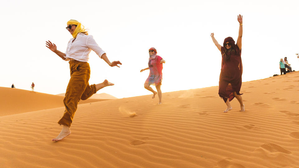 An image showing several people on a desert adventure, running through the sand.
