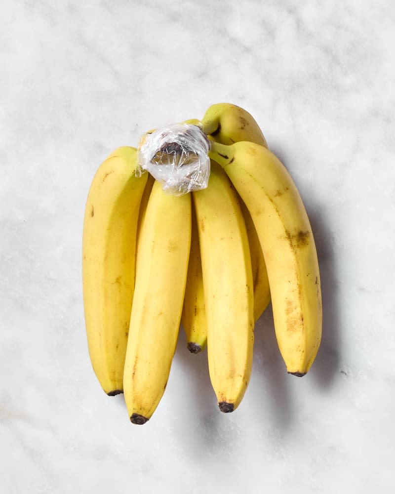 shot of a bunch of bananas with plastic wrap on the top of the stem