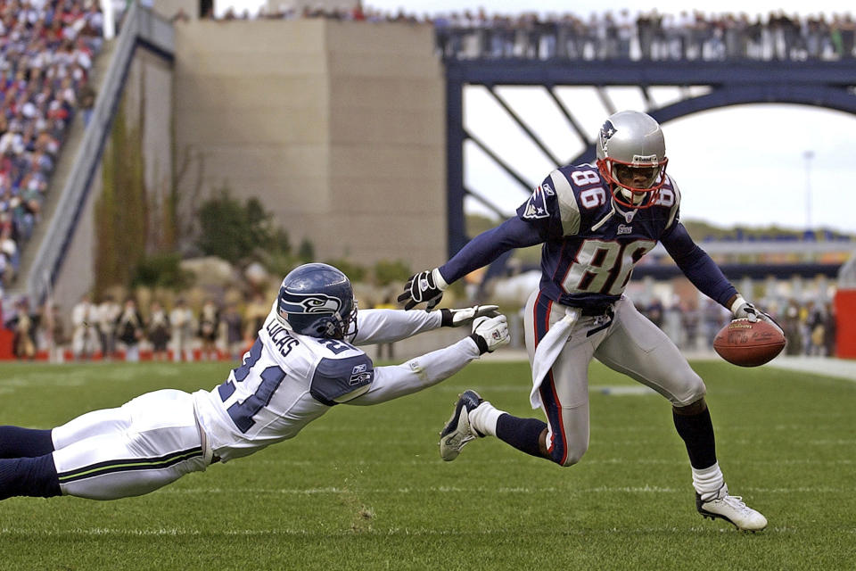 ARCHIVO - En imagen de archivo del 17 de octubre de 2004, el wide receiver David Patten (86), de los Patriots de Nueva Inglaterra, evade la tacleada del cornerback Ken Lucas, de los Seahawks de Seattle, rumbo a la zona de anotación en el segundo cuarto de un partido de NFL en Foxborough Massachusetts. (AP Foto/Adam Hunger, archivo)